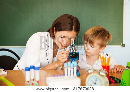 Schoolboy Looking Inot Microscope While The Biology Teacher Is Attending Him Back To School Concept.