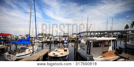 Boats In A Harbor Along The Caloosahatchee River With The Caloosahatchee Bridge In The Background In