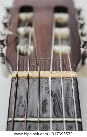 Focus On The Nut And Strings Of A Acoustic Guitar Headstock. Old Acoustic Guitar, Worn Out And Dusty