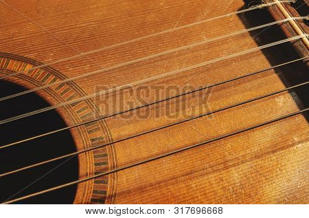 Shapes And Lines Of An Old Acoustic Guitar, Sound Hole, Part Of The Bridge And Old Rusty Nylon Strin