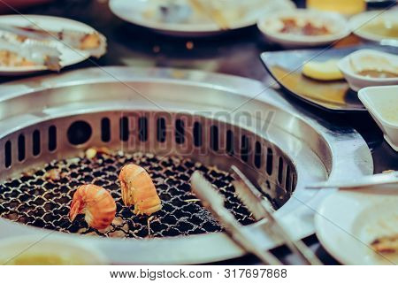 People Grilling Meat On A Smokeless Barbecue Grill In A Restaurant. Selective Focus On Shrimps.