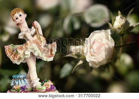 Vintage Girl Figurine Wearing Petticoat With Guitarre And A White Rose On Creamy Green Background. C