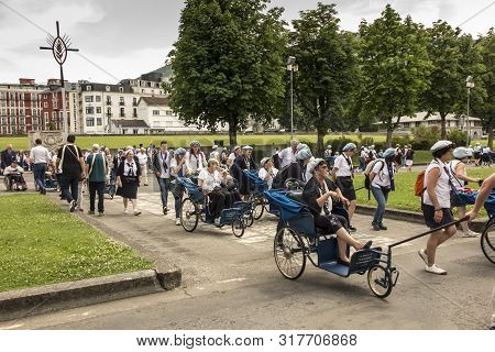 Lourdes, France June 24, 2019: Volunteers Helping The Sick Get To The Sanctuary Of Our Lady In Lourd