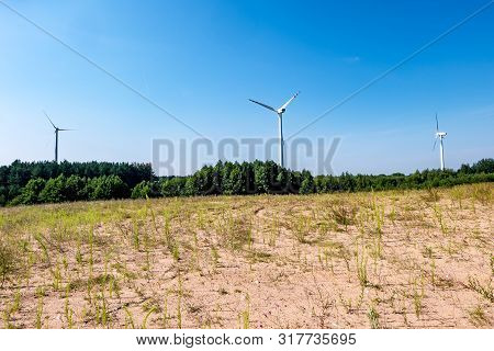 Rotating Blades Of A Windmill Propeller On Blue Sky Background. Wind Power Generation. Pure Green En