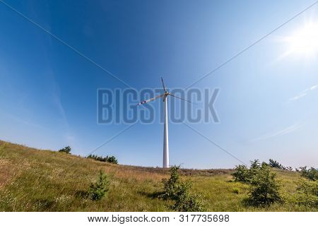 Rotating Blades Of A Windmill Propeller On Blue Sky Background. Wind Power Generation. Pure Green En