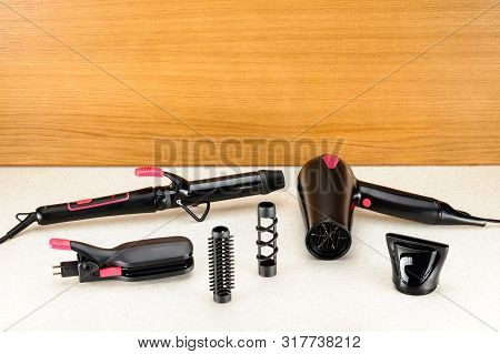 Electrical Hair Iron And Dryer For Household On The Woody Marbled Background With Copy Space