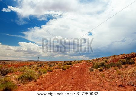 Red Dirt Road In The Desert Of Page, Arizona.  Desert Path With Shrubs In The Foreground, Powerlines