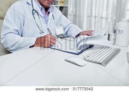 Cropped Image Of General Pratitioner Filling Document With Medical History Of Patient