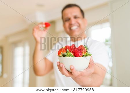 Middle age man eating straweberry at home