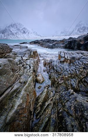 Waves and rocks on coast of Norwegian sea in fjord. Skagsanden beach, Flakstad, Lofoten islands, Norway. Long exposure motion blur