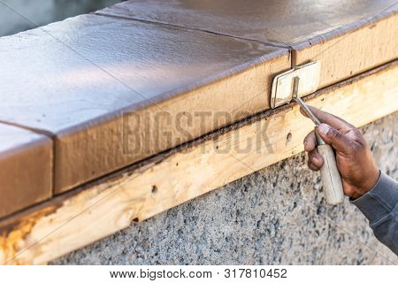 Construction Worker Using Hand Groover On Wet Cement Forming Coping Around New Pool.