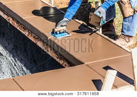 Construction Worker Using Hand Groover On Wet Cement Forming Coping Around New Pool.