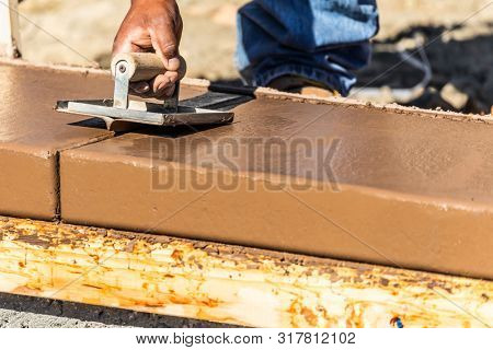Construction Worker Using Hand Groover On Wet Cement Forming Coping Around New Pool.
