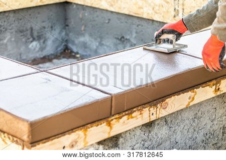 Construction Worker Using Hand Groover On Wet Cement Forming Coping Around New Pool.