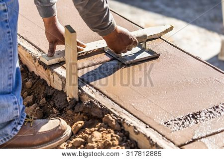 Construction Worker Using Hand Groover On Wet Cement Forming Coping Around New Pool.