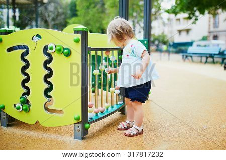 Adorable Toddler Girl Having Fun On Playground. Outdoor Activities For Kids