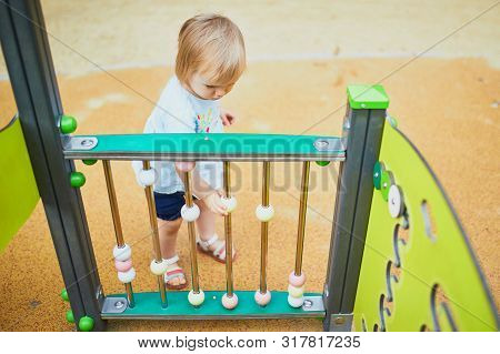 Adorable Toddler Girl Having Fun On Playground. Outdoor Activities For Kids