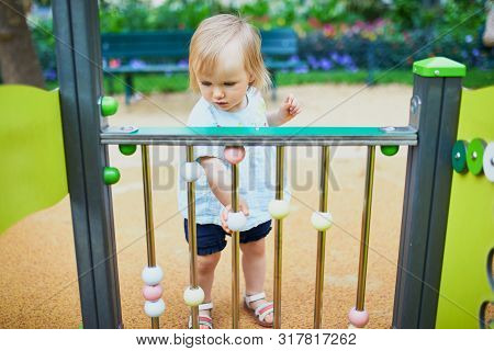 Adorable Toddler Girl Having Fun On Playground. Outdoor Activities For Kids