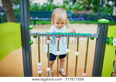 Adorable Toddler Girl Having Fun On Playground. Outdoor Activities For Kids