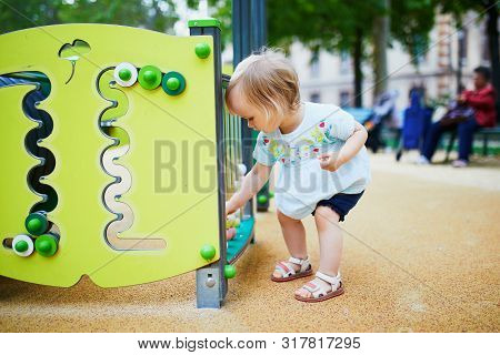 Adorable Toddler Girl Having Fun On Playground. Outdoor Activities For Kids