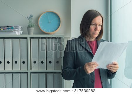 Concerned Businesswoman Reading Business Report Papers In Office, Financial Data Analysis And Strate