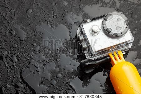 Action Camera In A Waterproof Box And A Buoy For Diving In Water Drops On A Black Background. Copy S