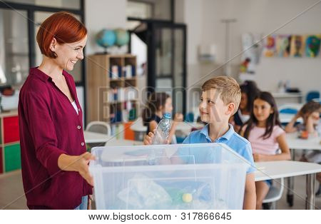 A Teacher With Small School Kids In Classroom Learning About Waste Separation.