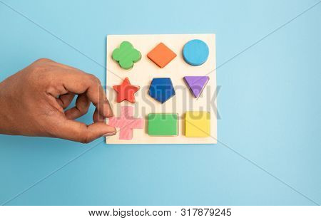 Top View Hands Picking Up One Colorful Wooden Building Blocks In Different Shapes On Blue Background