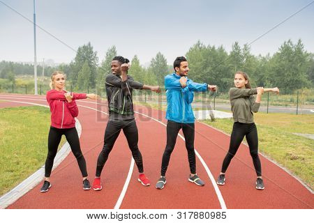 Young men and women in activewear exercising on race tracks