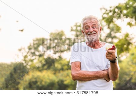 Elder Healthy Man Eating Apple Fruit In Plublic Park Morning.