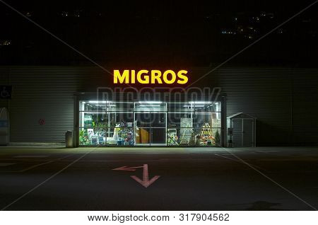 Agno, Ticino, Switzerland - 23rd July 2019 : View Of A Migros Supermarket Entrance At Night. Migros 