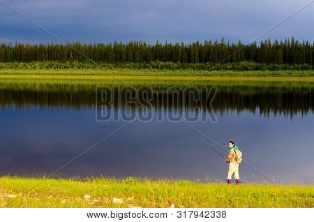 Yakut Girl Tourist With A Backpack Angler Catches A Fish And Throws Bait Spinning Reel On A Wild Nor