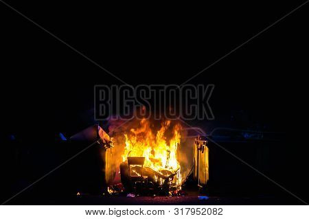 Burning Trash Container And Old Wood Chair With Other Garbage Close Up. Plastic Garbage Can Has Almo