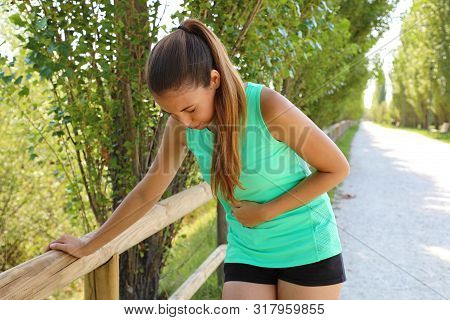 Woman Has Side Cramp. Young Woman Suffering From Abdominal Pain While Running Outdoor.