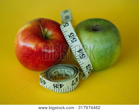 Bodegon Mounted On A Yellow Background And Composed Of Two Apples And A Tape To Measure The Waist