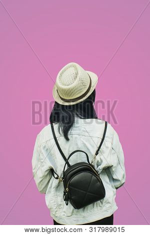 Portrait  Back Of An Asian Woman Jean Jecket And Straw Hat Isolated Over Pink Background