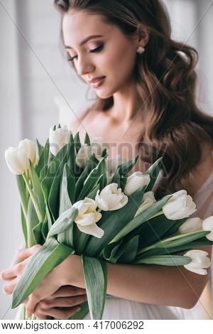 Wedding Bouquet Of White Tulips In The Hands Of A Beautiful Bride Indoor. Selective Soft Focus
