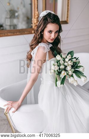 Young Bride In Wedding Dress Holding Bouquet Of White Tulips In Studio