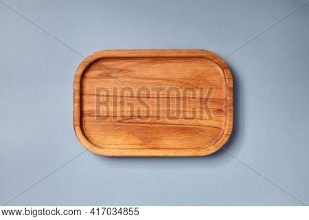 Empty wooden tray on textured dark blue table. Rectangular wooden dish top view. Kitchen minimal flat lay