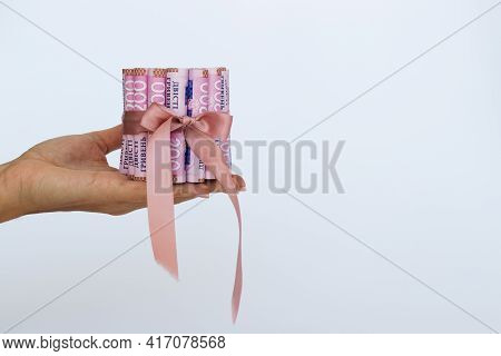 Female Hand Holding Ukrainian Money Wrapped With A Gift Ribbon.