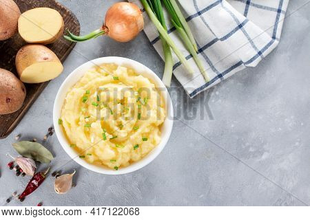 Mashed Potatoes With Butter And Fresh Parsley In A White Bowl On Gray Stone Concrete Background. Top