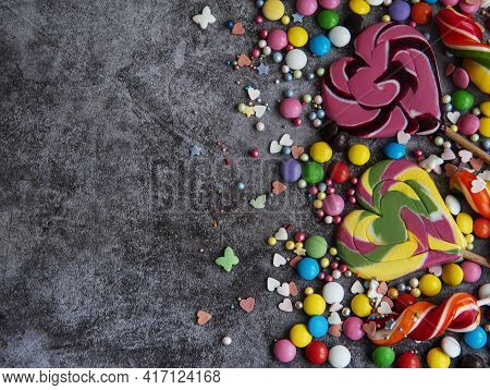 Multicolored Candies, Dragees And Lollipops On A Black Background