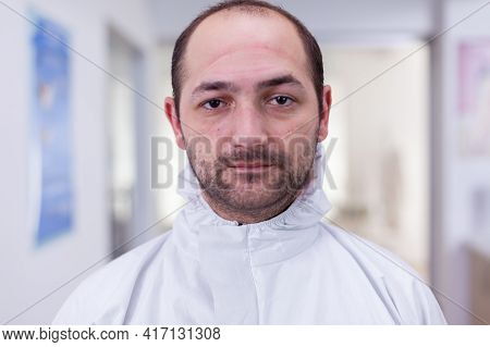 Portrait Of Exhausted Doctor In Office Looking On Camera Wearing Ppe Suit