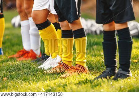 A Row Of Legs Of Young Soccer Players. Boys Standing In A Row In Football Cleats. Soccer Socks And S