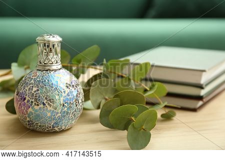 Stylish Catalytic Lamp With Eucalyptus And Books On Wooden Table In Living Room, Closeup. Cozy Inter