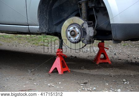 Car Repair At Home In The Yard. The Car Is Without Wheels And The Brake System Is Checked. Red Pyram