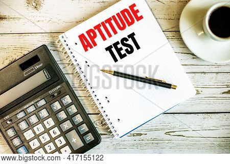 Aptitude Test Written On White Paper Near Coffee And Calculator On A Light Wooden Table. Business Co