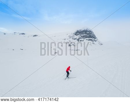 Cross Country Skier Traveling Across A Snowy Arctic Tundra In The High Mountains On A Cold Winters D