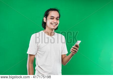 Handsome Asian Man Holding Handphone With Happiness Smile Expression While Looking At The Camera