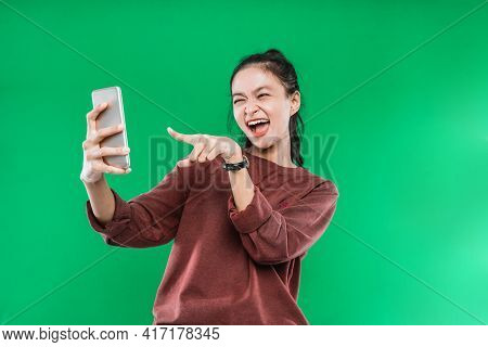 Beautiful Young Woman Being Video Call With Someone While Pointing At The Telephone With A Happy Exp